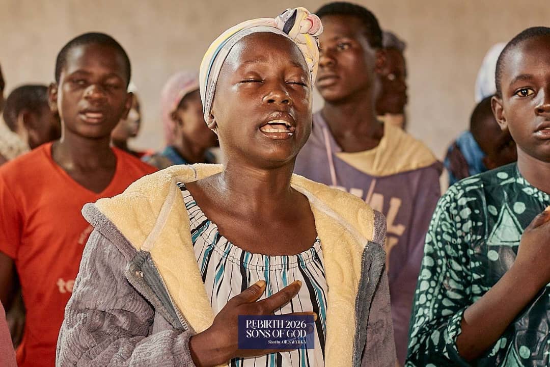 A child in a headwrap standing among other children.