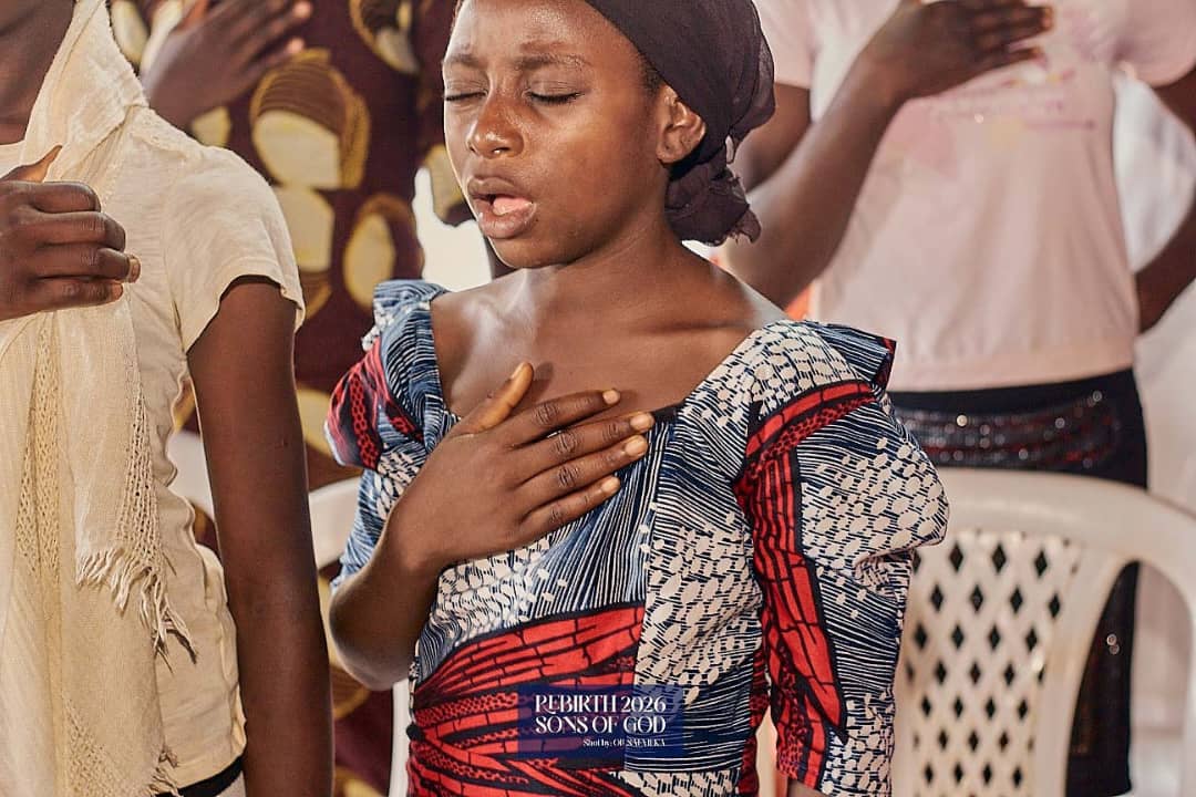 A child standing with a hand resting on her chest.