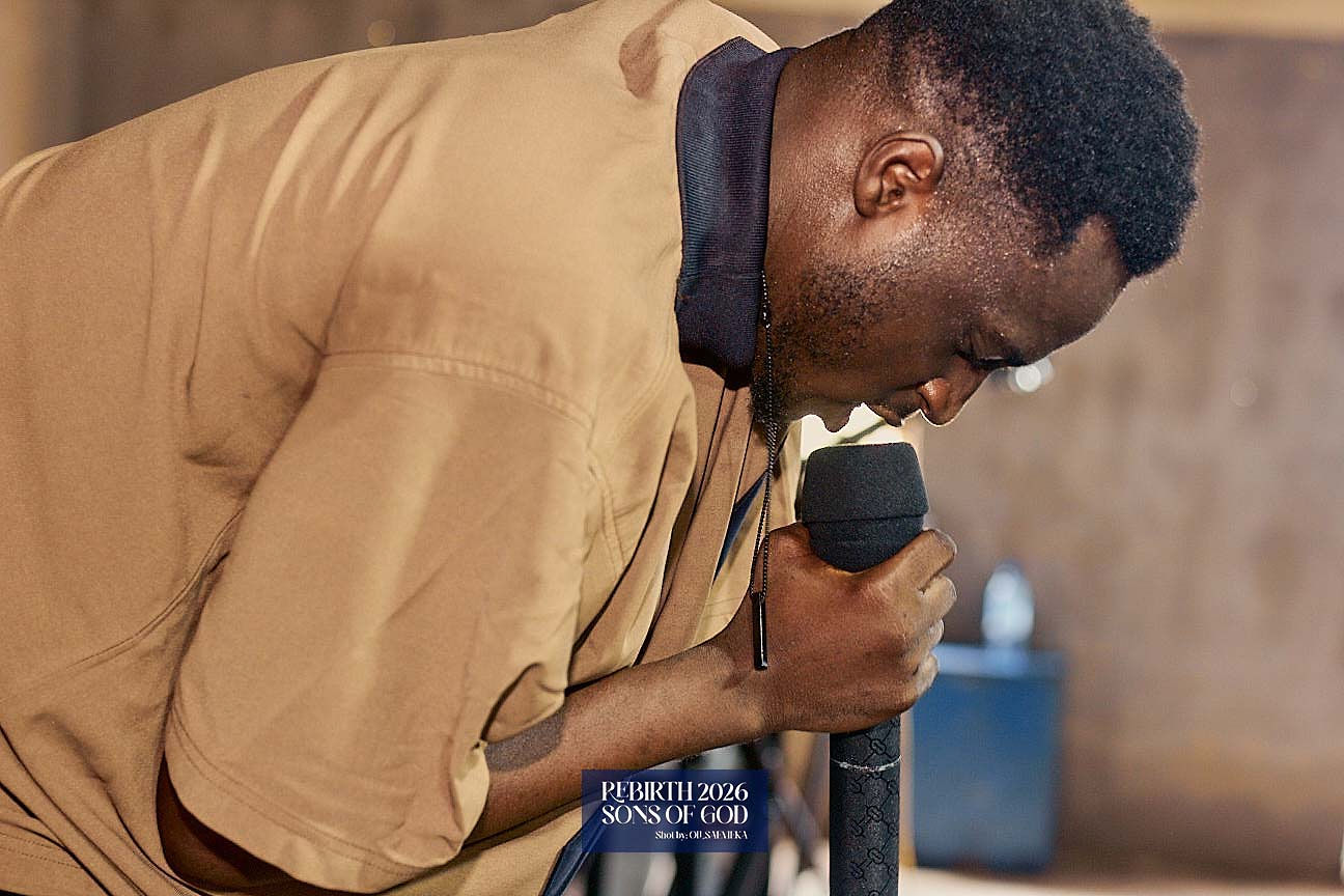 A speaker leaning forward while holding a microphone.