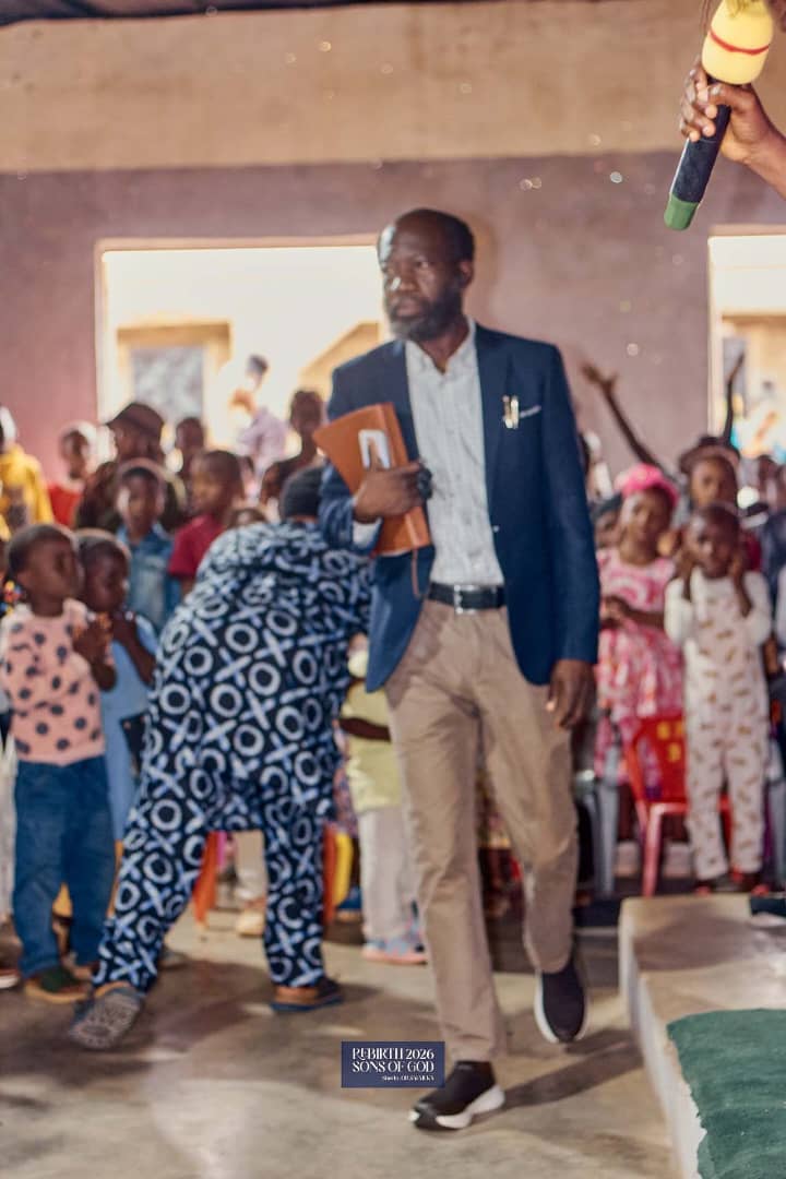An adult holding a book at an indoor gathering.