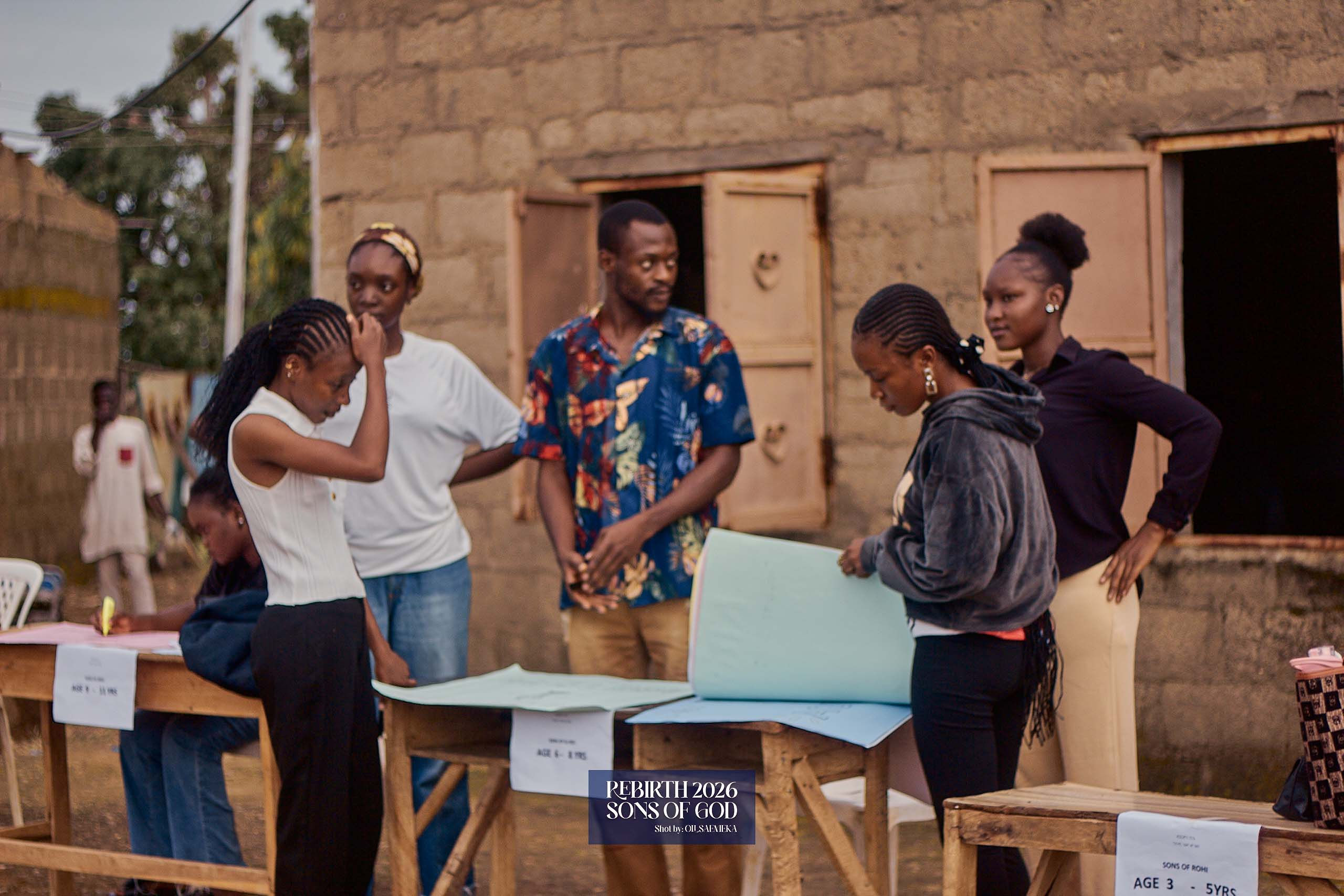 Volunteers arranging papers at tables outside a building.