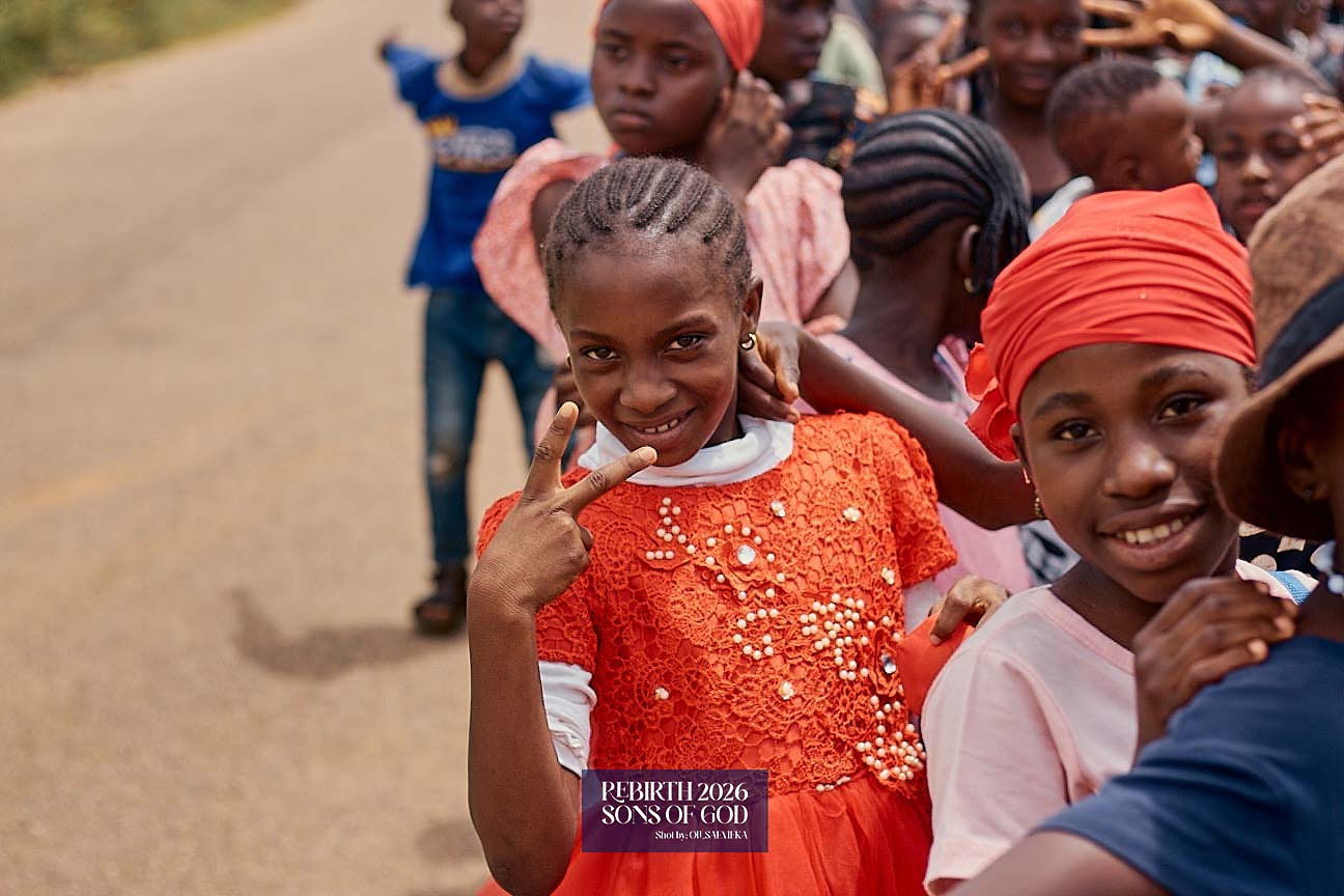 Children smiling for the camera while gathered outdoors.