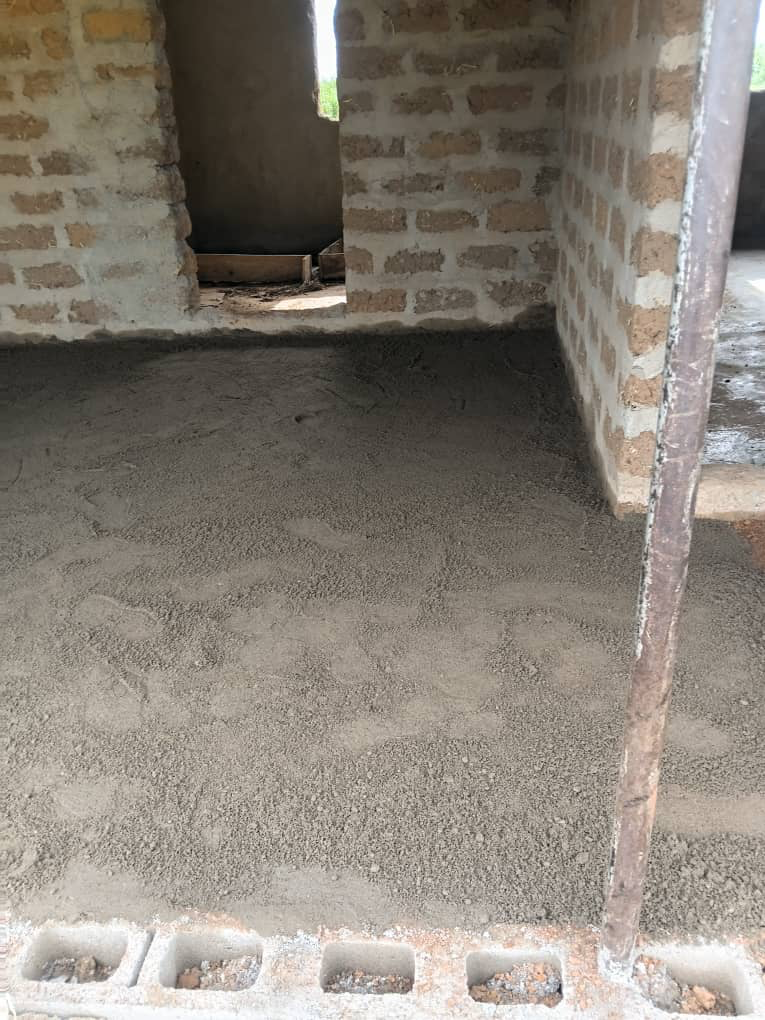 Flooring being laid inside a classroom with unfinished block walls.